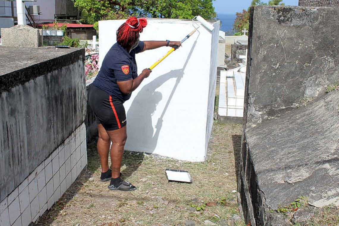 Firefighters paint the tombs  of fallen firefighters in Statia